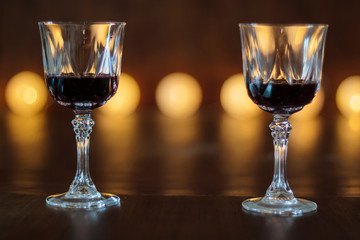 Two glasses of red wine with defocused lights on the background