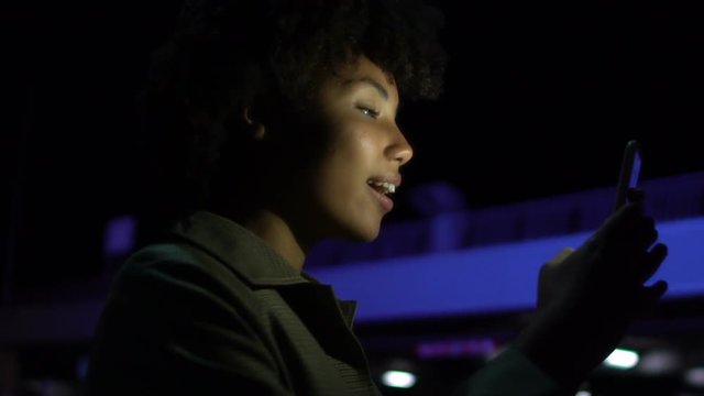 Attractive girl making selfie on smartphone at night time, smiling into camera