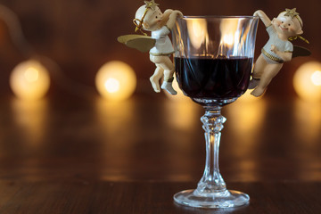Glass of red wine with Christmas decoration with lights in the background
