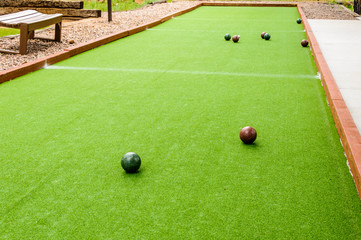 Five Bocce Balls and on a green bocce court.