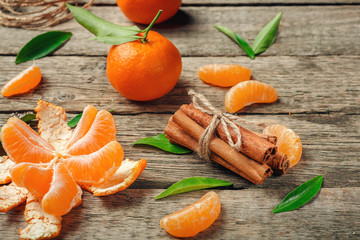 Tangerines with leaves and cinnamon stick on old wooden table. Top view.  Selective focus