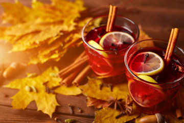 Autumn warming drink. Hot mulled wine, with lemon, anise, cinnamon, cloves, cardamom. Autumn dark still life. Mulled wine with slice of lemon and spices.