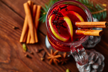 Christmas mulled wine with spices in cup on dark background. Hot mulled wine, with lemon, anise, cinnamon, cloves, cardamom. Autumn dark still life. Mulled wine with slice of lemon and spices.