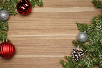 Christmas decoration on wooden textured background. Ornaments arranged creatively around the borders with fir leaves. Seasons greetings. Flat lay or top view.