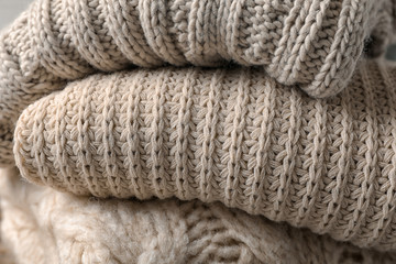 Stack of folded warm knitted sweaters, closeup