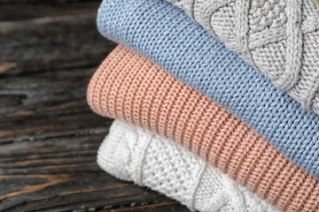 Stack of folded knitted sweaters on table, closeup