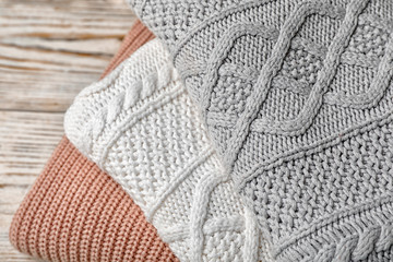 Stack of folded knitted sweaters on table, closeup