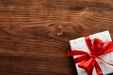 Christmas Gift boxes and decorations. Gift box in kraft paper with a red ribbon on a wooden background. Christmas background.