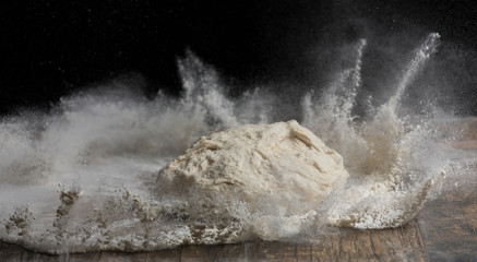 Studio close-up photo of a ball of dough falling on flour