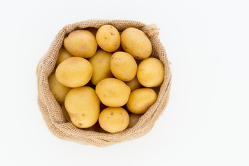 Sack of fresh raw potatoes on wooden background, top view