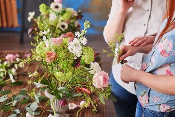 hands of florist collect wedding bouquet at work
