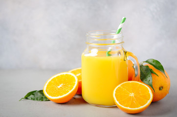 Obraz na płótnie Canvas Fresh orange juice in a jar on gray concrete background, selective focus, copy space.