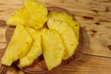 Pieces of pineapple on a cutting board on wooden table. Top view