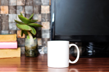computer screen on work desk with black screen, coffee cup, books and plante on wooden table