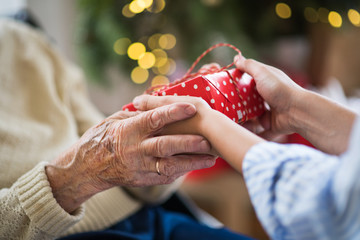Close-up of hands of senior and young woman holding a present at Christmas.