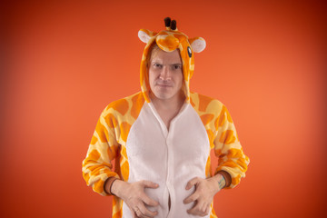 pajamas in the form of a giraffe. emotional portrait of a guy on an orange background. crazy and...