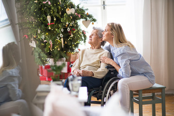 A senior woman in wheelchair with a health visitor at home at Christmas time.