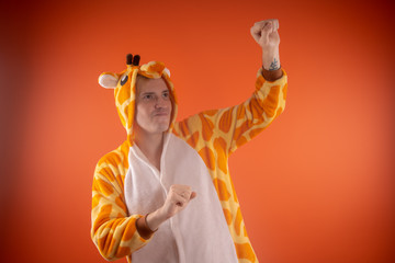 pajamas in the form of a giraffe. emotional portrait of a guy on an orange background. crazy and funny man in a suit. animator for children's parties