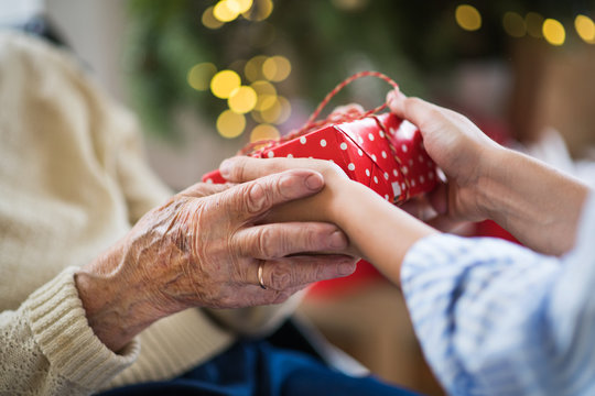 Close-up of hands of senior and young woman holding a present at Christmas.