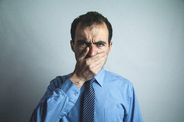 Caucasian man with hand closed his mouth.