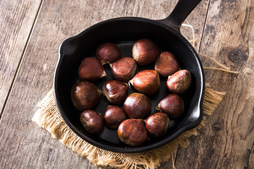 Obraz premium Chestnuts in iron pan on wooden table