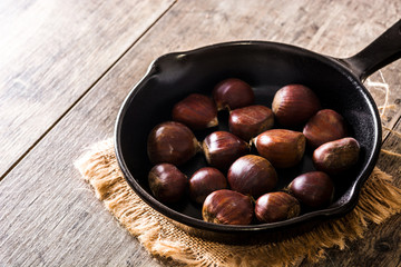 Chestnuts in iron pan on wooden table

