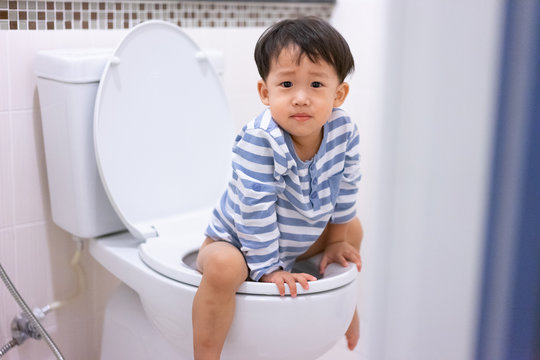 Little boy poo and pee in white toilet.