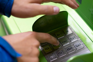 close up person hand push buttons and enter credit card code on atm in bank f
