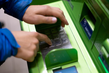 close up person hand push buttons and enter credit card code on atm in bank f