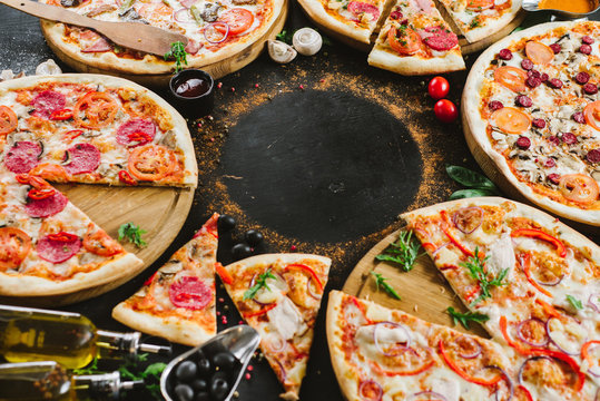 Many kinds of tasty pizzas on black background. Flatlay. Copy space