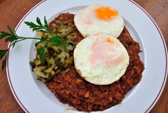 Traditional Bremen style &ldquo;Seemannslabskaus&rdquo; made of corned beef and mashed potatoes with two fried eggs, and strips from gherkin