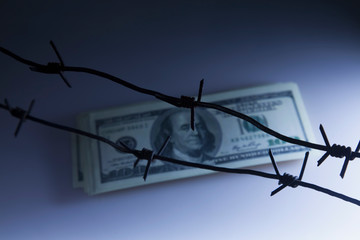 US Dollar money wrapped in barbed wire as symbol of economic warfare, sanctions and embargo busting