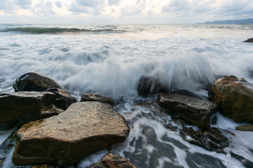 Seascape with waves hitting the stones, sunset
