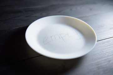 white plate with an inscription it is empty on a black wooden background. A concept for weight loss and dietary food. a concept on a hunger in Africa