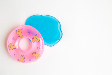 Flat lay of pool float and blue jelly in form of water abstract on white background.