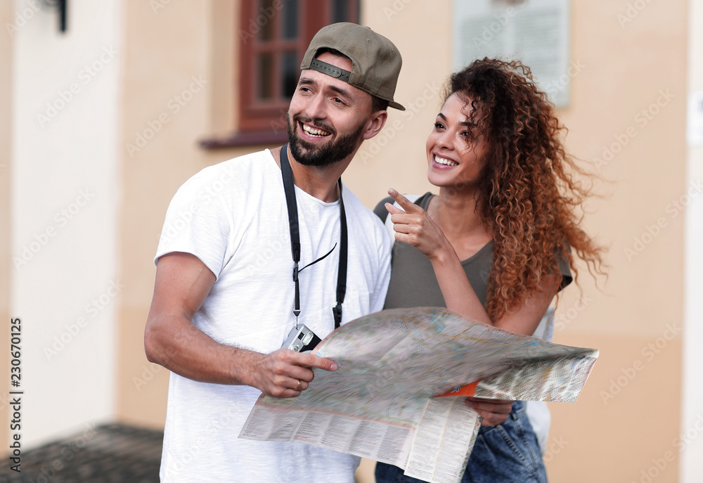 Wall mural Young tourist couple with map looking for a way