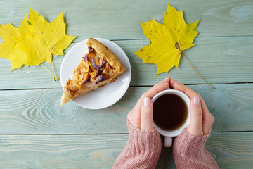 Naklejka na ściany i meble Girl in a sweater warms her hands about a cup of tea, apple pie