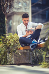 Fototapeta premium Man standing alone on the street, looking at his tablet
