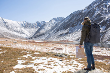 Fototapeta premium man stands on a background of mountains and holds a map in his hand