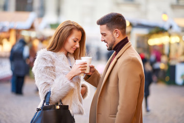 A beautiful young couple drinking mulled wine in a christmas market.