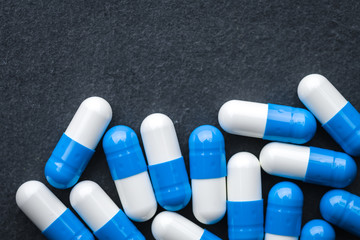 White And Blue Drugs, Pills, Vitamins Scattered On A Gray Slate Background. Medical Series. Free Space For Text. Close Up. Top View. Rustic Style.