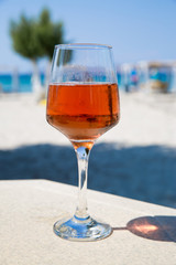 One glass of cold rose wine served on the beach with beautiful sea view. Relax concept. Bright sunny day with blue sky.
