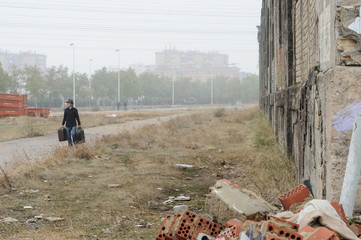 Hombre caminando con maleta y sombrero negro 34