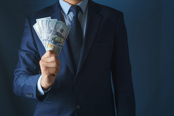 A man in a suit holds in his hand a fan of money.