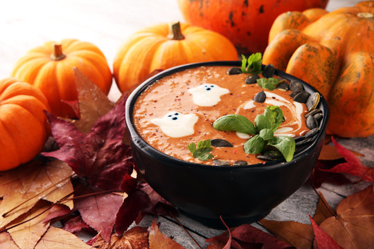 Roasted pumpkin and carrot soup with cream and pumpkin seeds on wooden background.