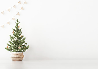 Interior white wall mock up with decorated christmas tree in basket and flag garland on empty background. 3D rendering.
