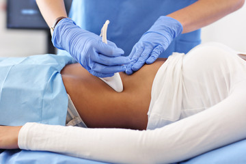 Adult woman having abdomen ultrasound tests at female doctor's office