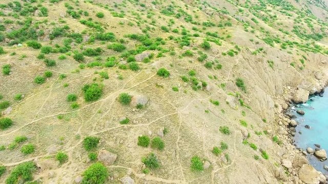 Drone shadow flying over rocks and land to cliffed Meganom, Crimea Rocks and Black sea, Tropical beatch 4K.