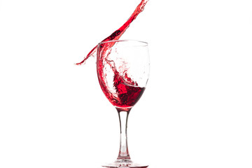 Red wine falls into a glass and creates splash and splashes on a white background.
