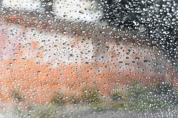Raindrops on the car window in the city in autumn